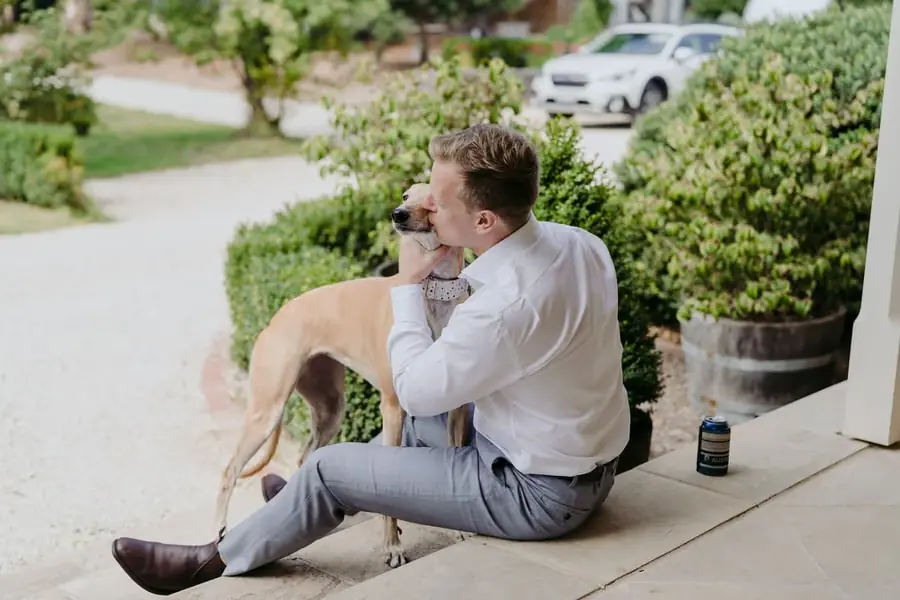 Man sitting on verandah steps and hugging a tan dog