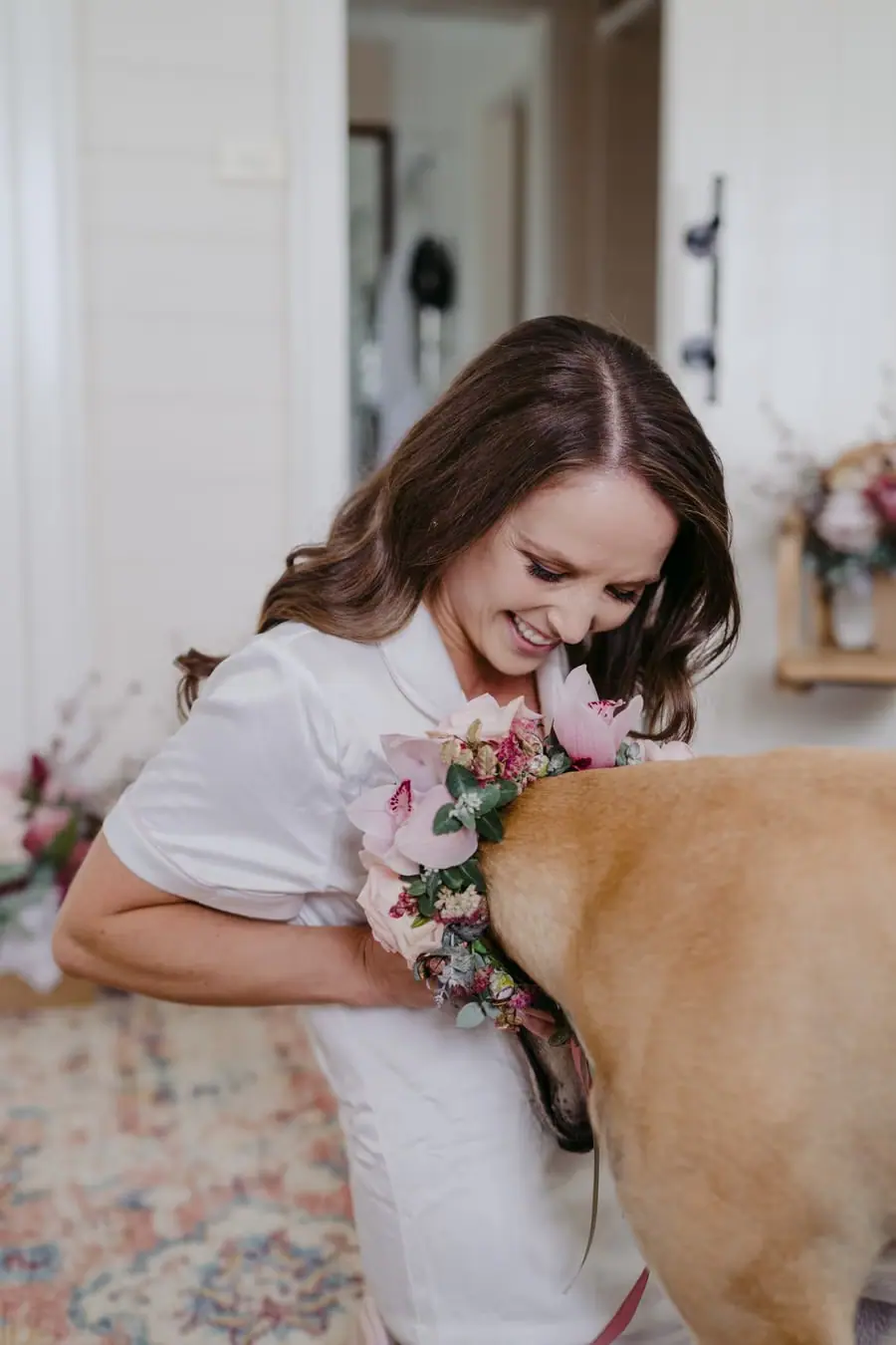 Bride smiling down at a dog beside a bouquet of flowers