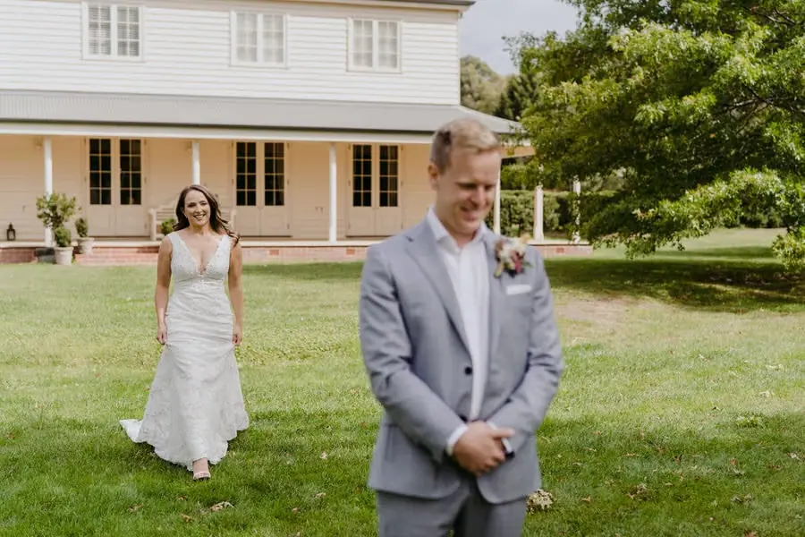 Bride smiling while walking toward the groom across the lawn
