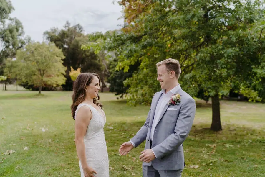Bride and groom smiling face to face in a garden