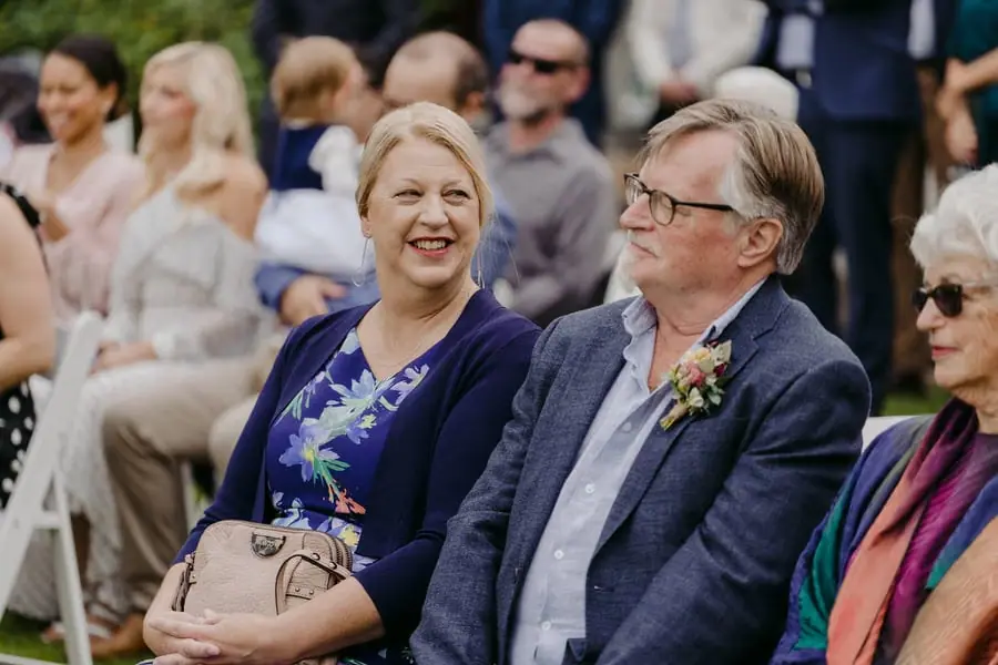Two seated guests smiling toward one another during the ceremony