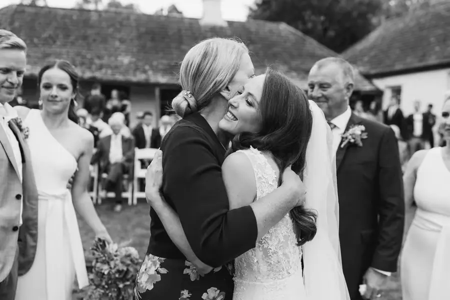 Black-and-white photograph of the bride hugging a guest after the ceremony