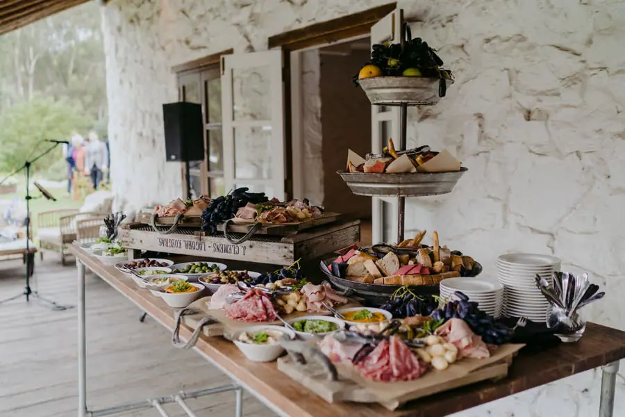 Grazing-food display arranged on a wooden table beside a stone wall