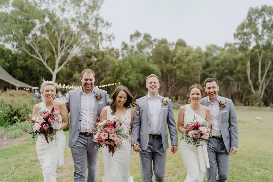 Wedding party walking together across a grassy lawn