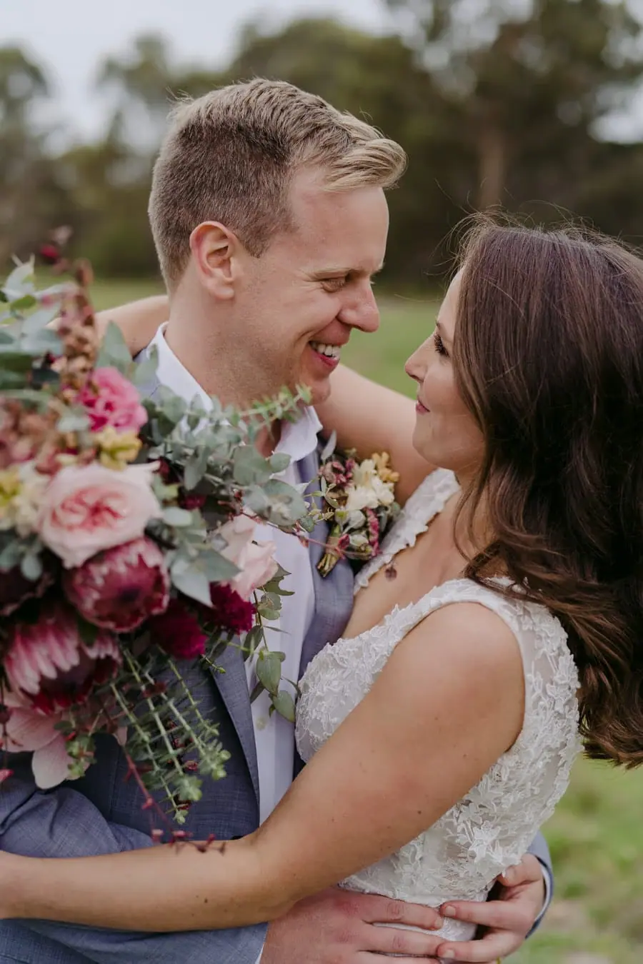 Bride and groom smiling closely together with a colourful bouquet