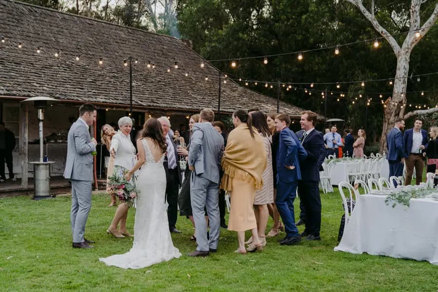 Bride and groom greeting guests beside outdoor reception tables