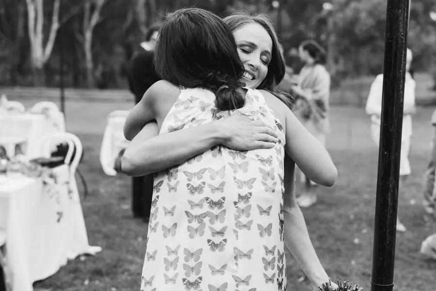 Black-and-white photograph of two wedding guests embracing outdoors
