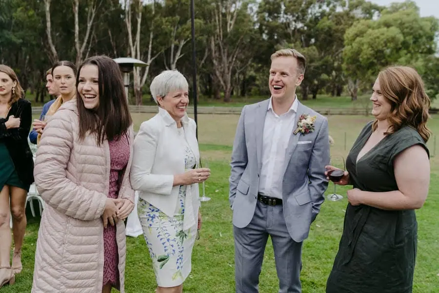Groom laughing with guests on the lawn beside the reception