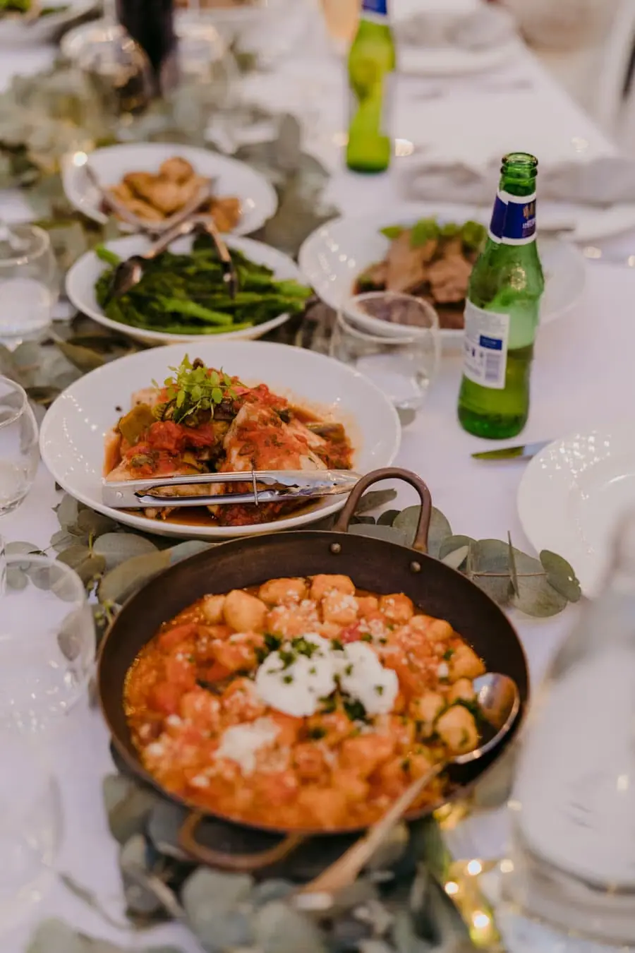 Shared food platters arranged along a white-clothed reception table