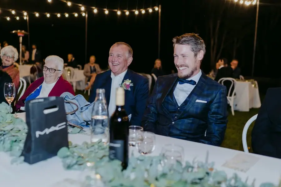 Seated guests smiling toward a speaker at the reception