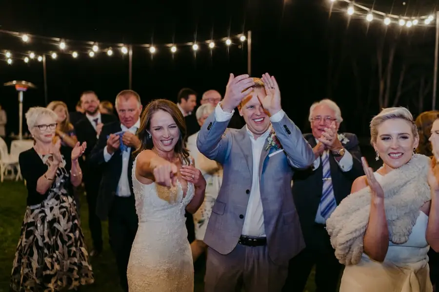 Bride, groom and guests cheering and recording with a phone