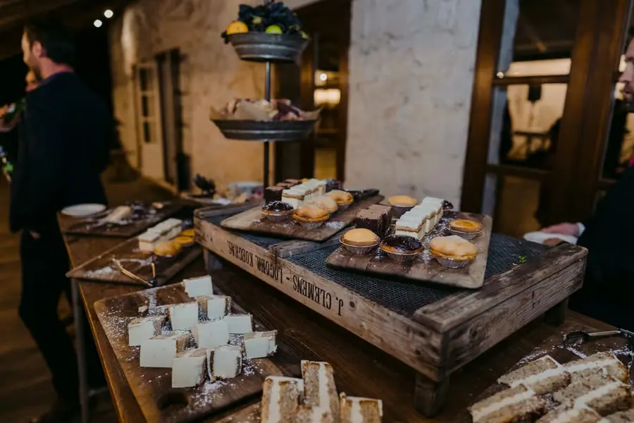Desserts and pastries displayed on wooden boards beside a stone wall