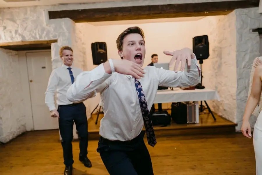 Guest gesturing playfully while dancing in a rustic reception room