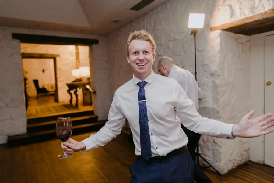 Man holding a wine glass and smiling with his arms spread