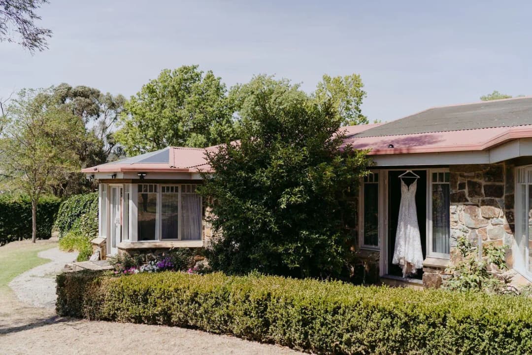 Sunlit cottage with a timber veranda, stone walls and a hedge-lined garden