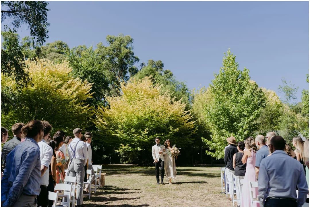 Bride walking toward the outdoor ceremony between standing guests.
