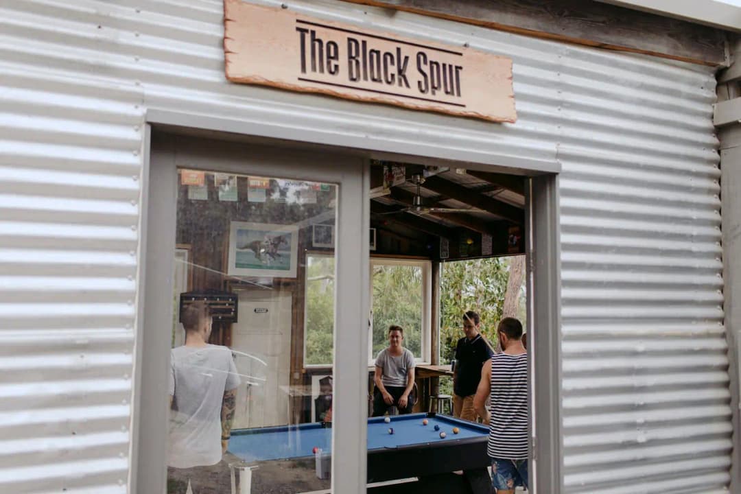 Guests gathered around a pool table beneath a sign reading The Black Spur