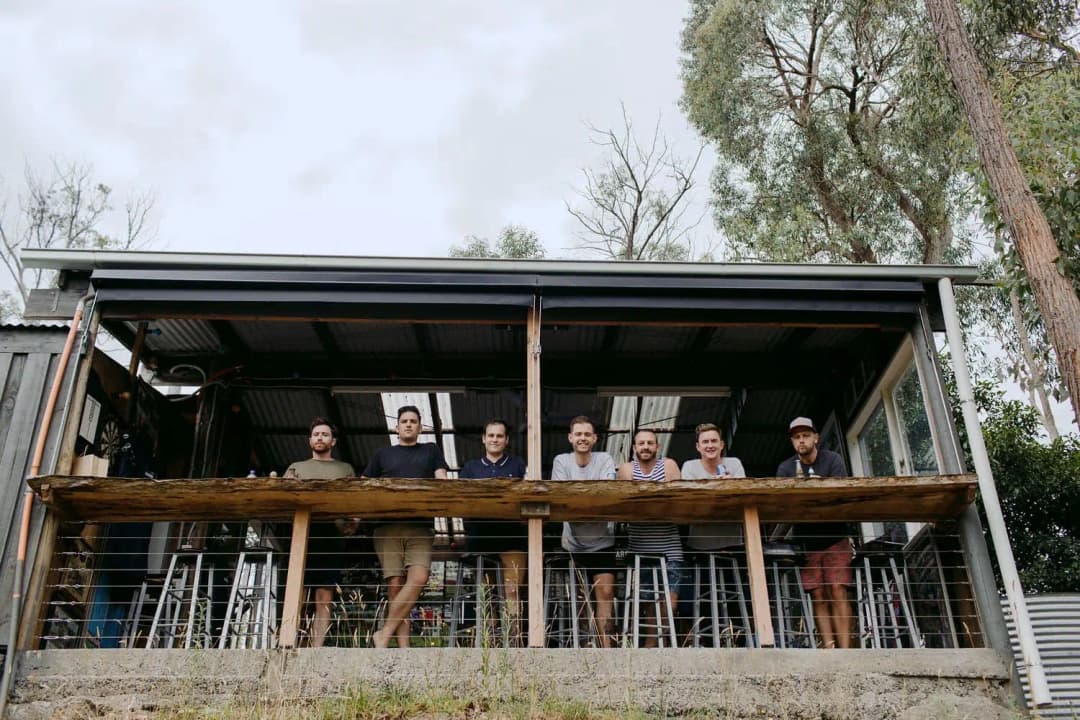 Group of men standing together on a timber balcony beneath a covered roof