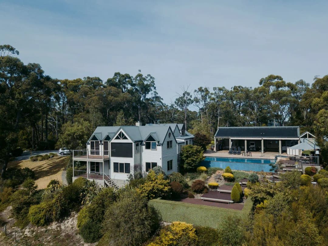 Elevated view of a white house, swimming pool and garden among trees