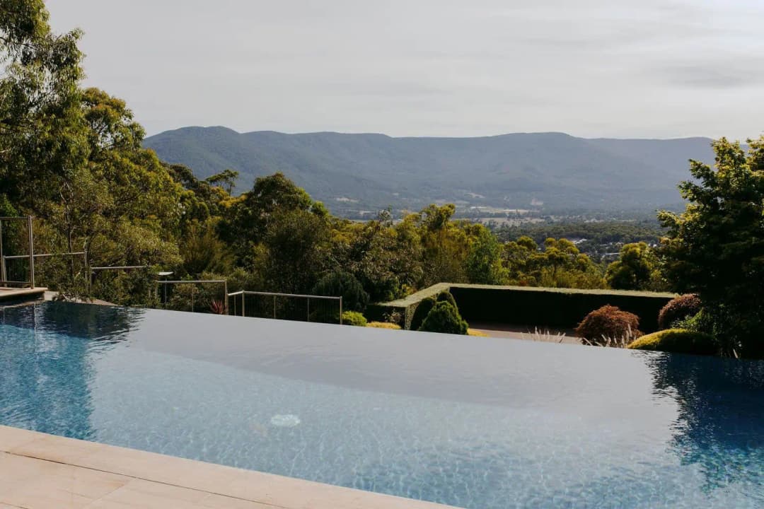 Infinity pool overlooking treetops, a valley and distant mountain ridges
