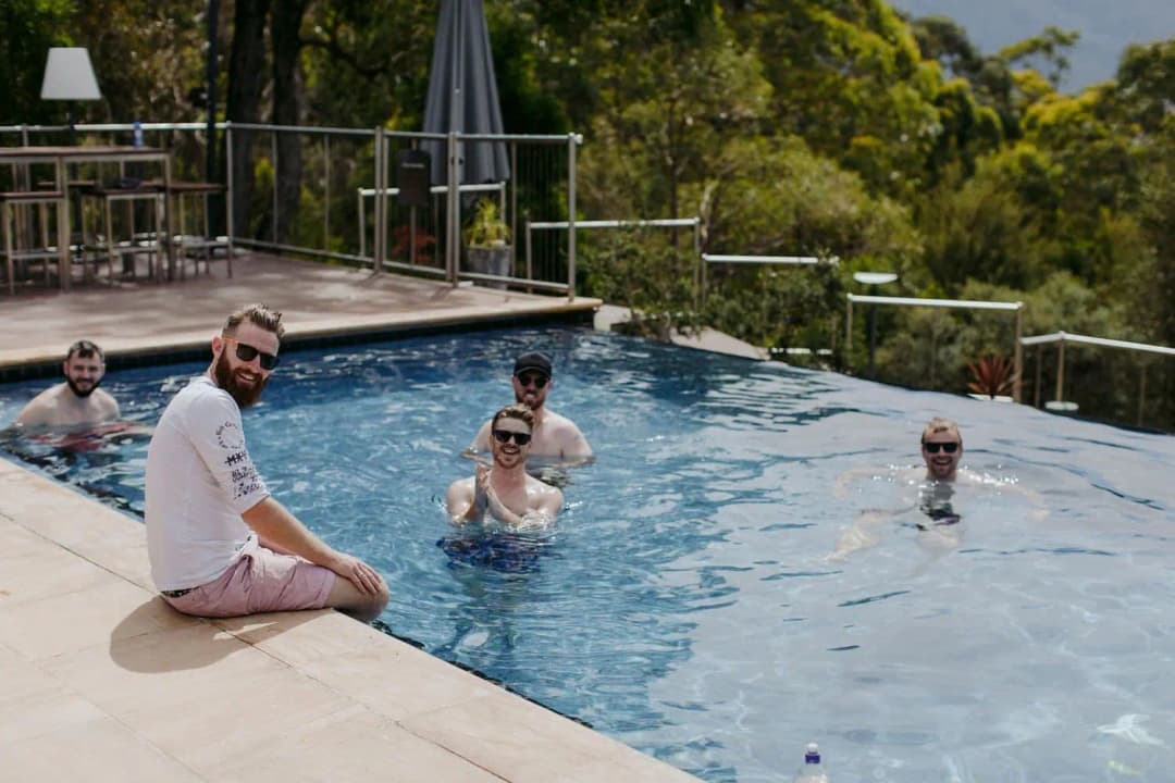 Men relaxing in a swimming pool with one seated on the edge