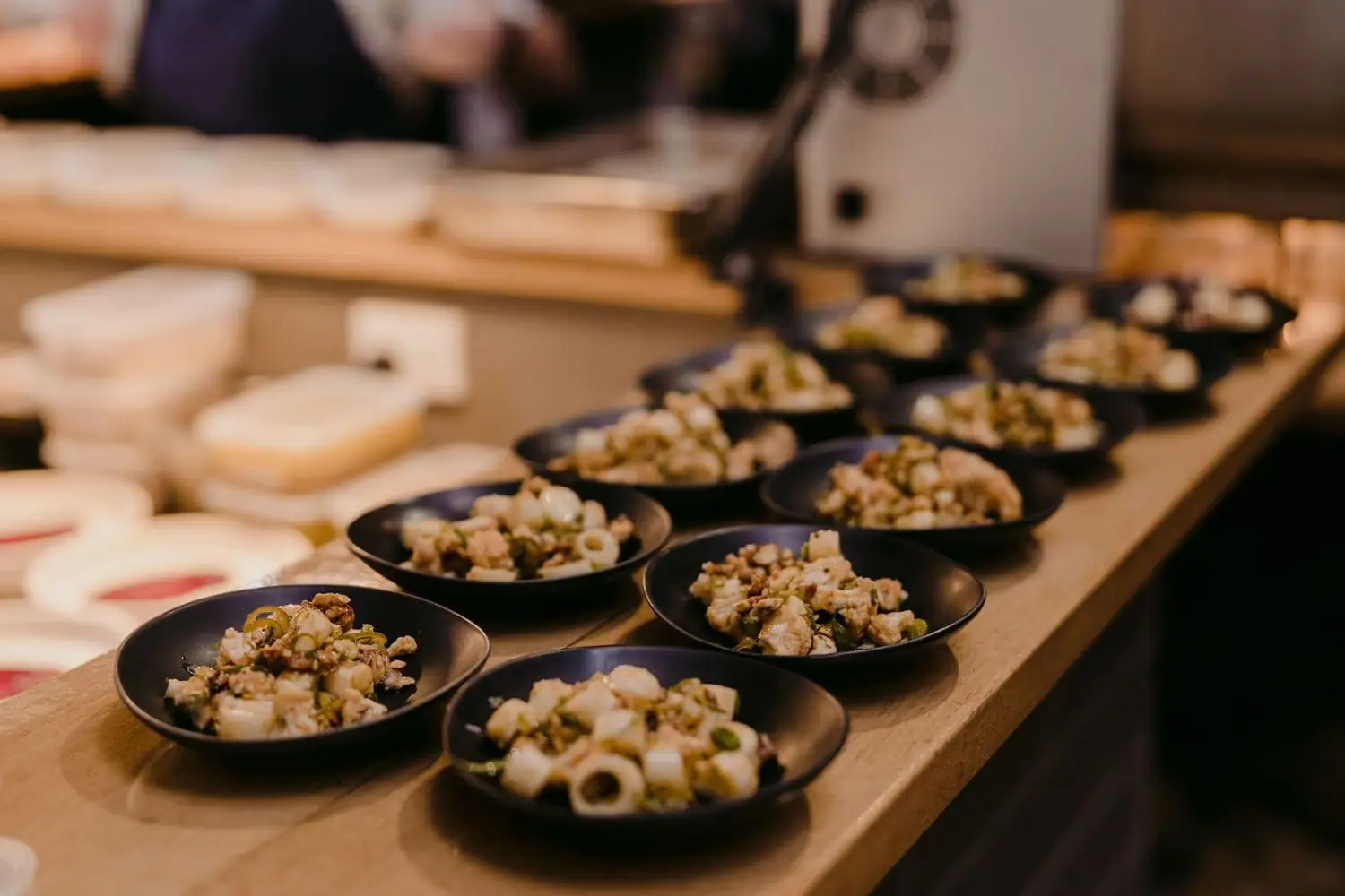 Black bowls of prepared food arranged along a kitchen counter.