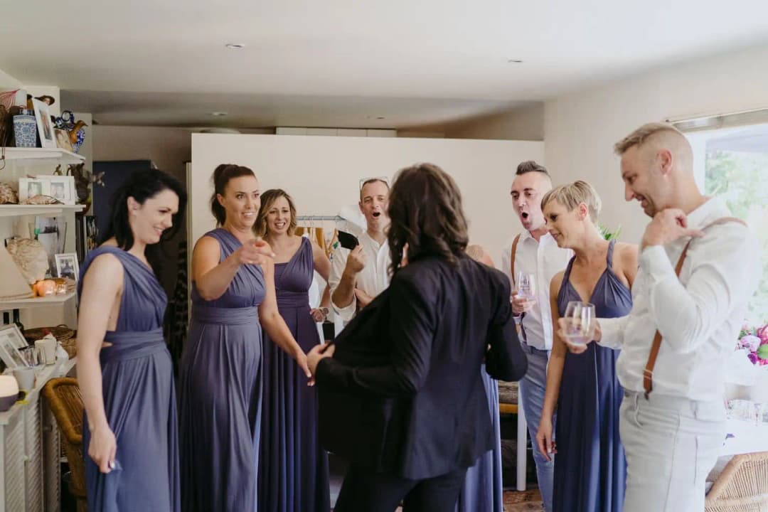 Wedding party raising glasses around a woman in a black suit