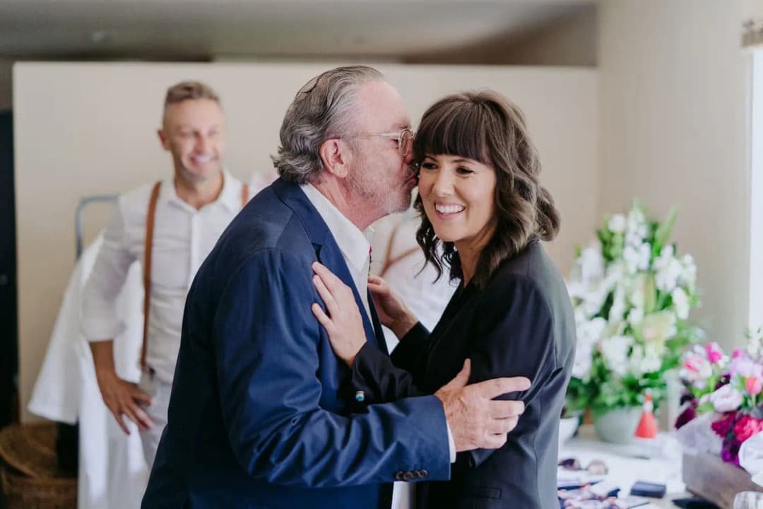 Older man kissing the smiling bride on the cheek