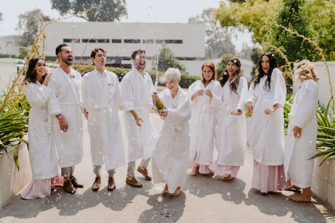 Wedding party in white robes gathered together in a sunny garden