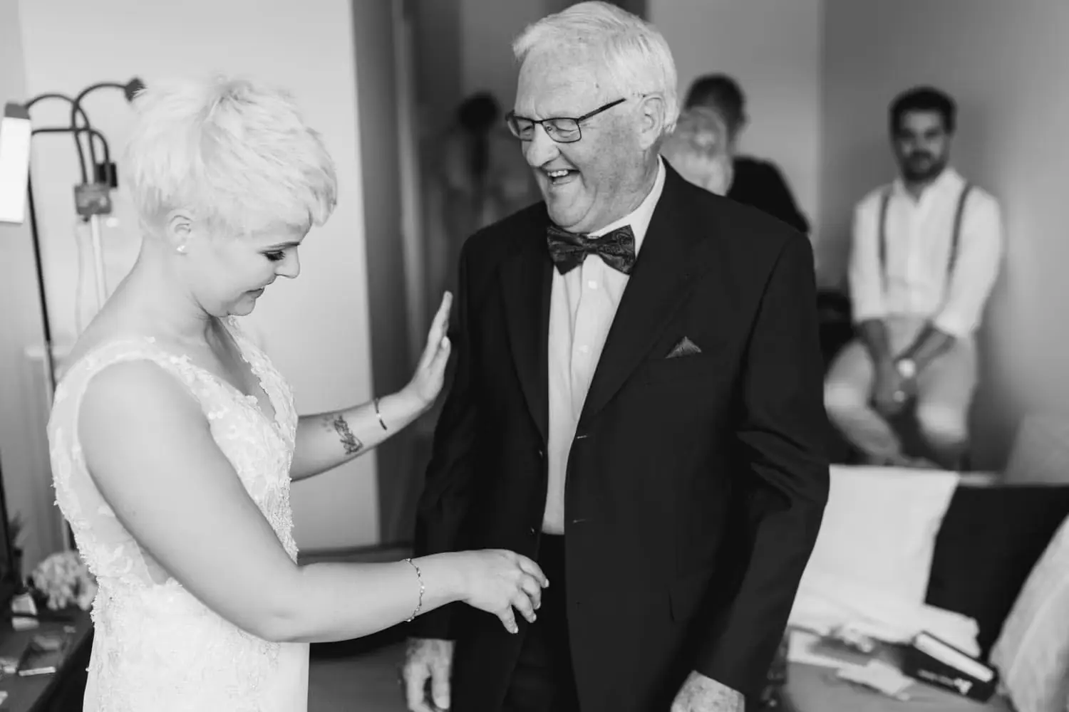 Black-and-white photograph of the bride greeting an older man in a bow tie