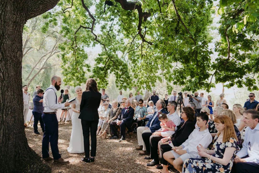 Wedding guests seated around the couple during an outdoor ceremony