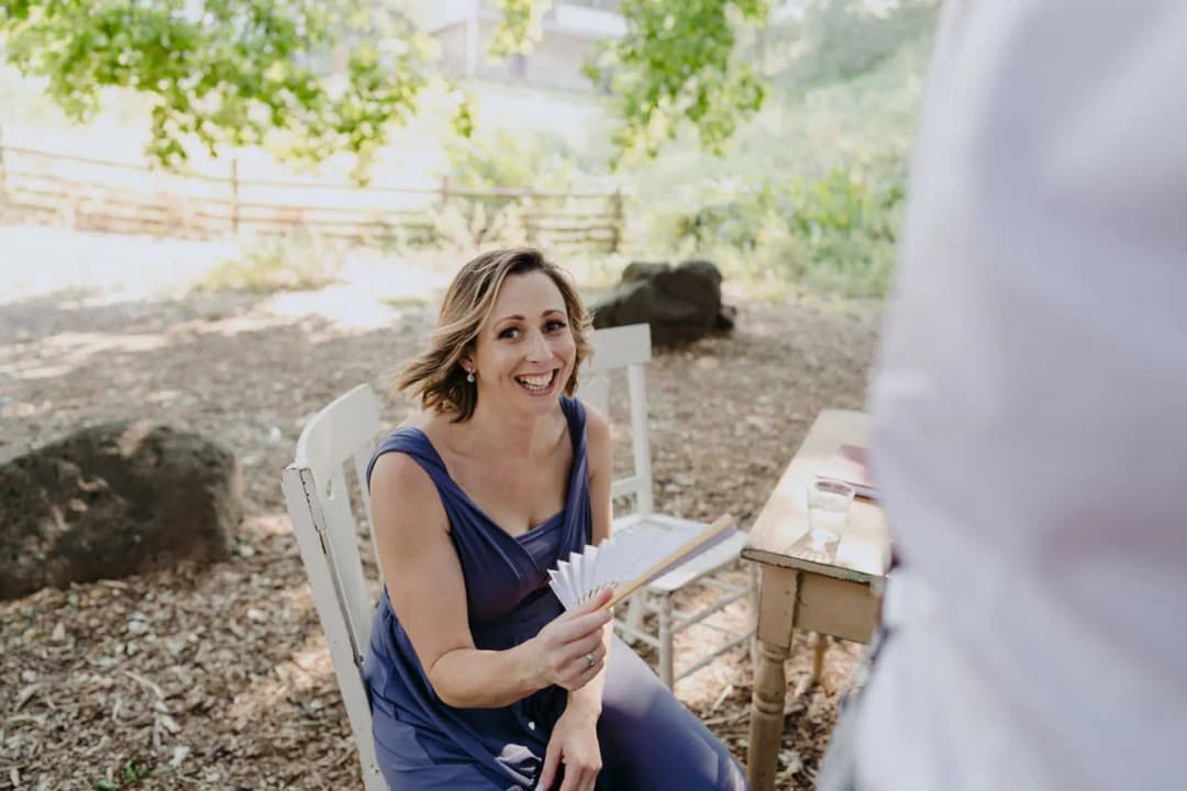 Guest in a blue dress smiling while holding ceremony notes