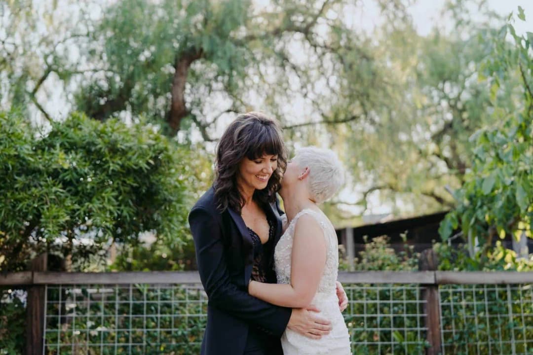 Couple embracing beside a wooden garden fence