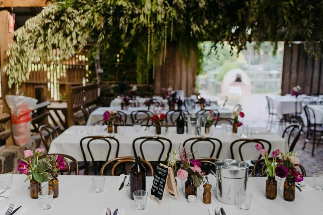 Long reception tables decorated with flowers beneath hanging greenery