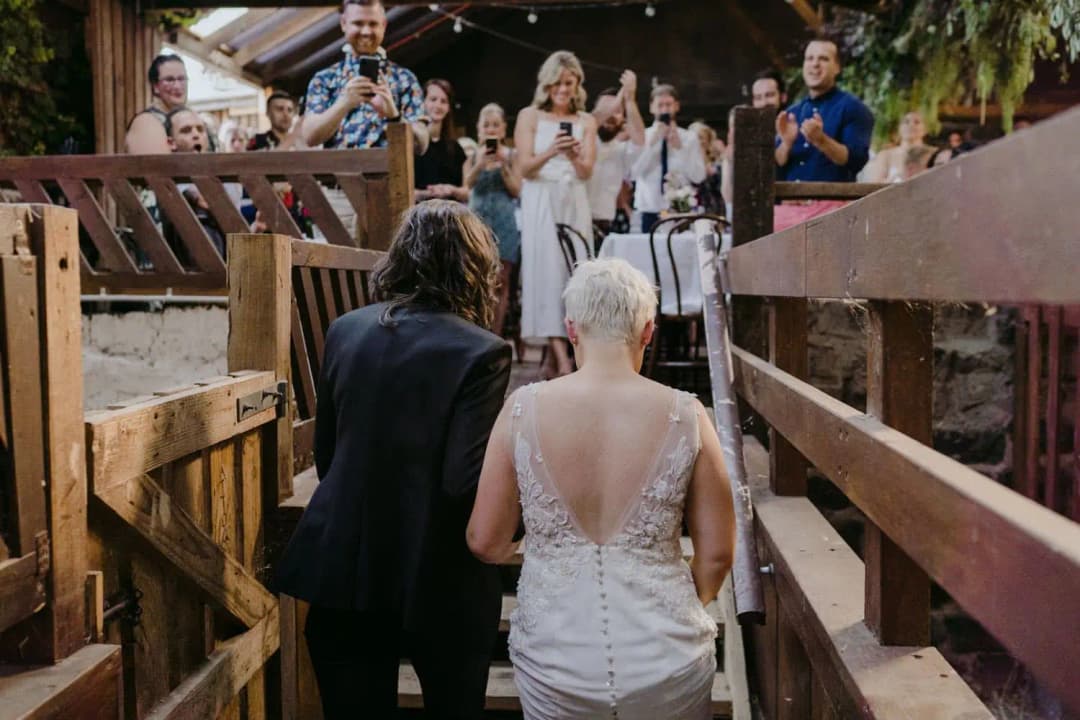 Couple walking toward applauding guests inside the barn