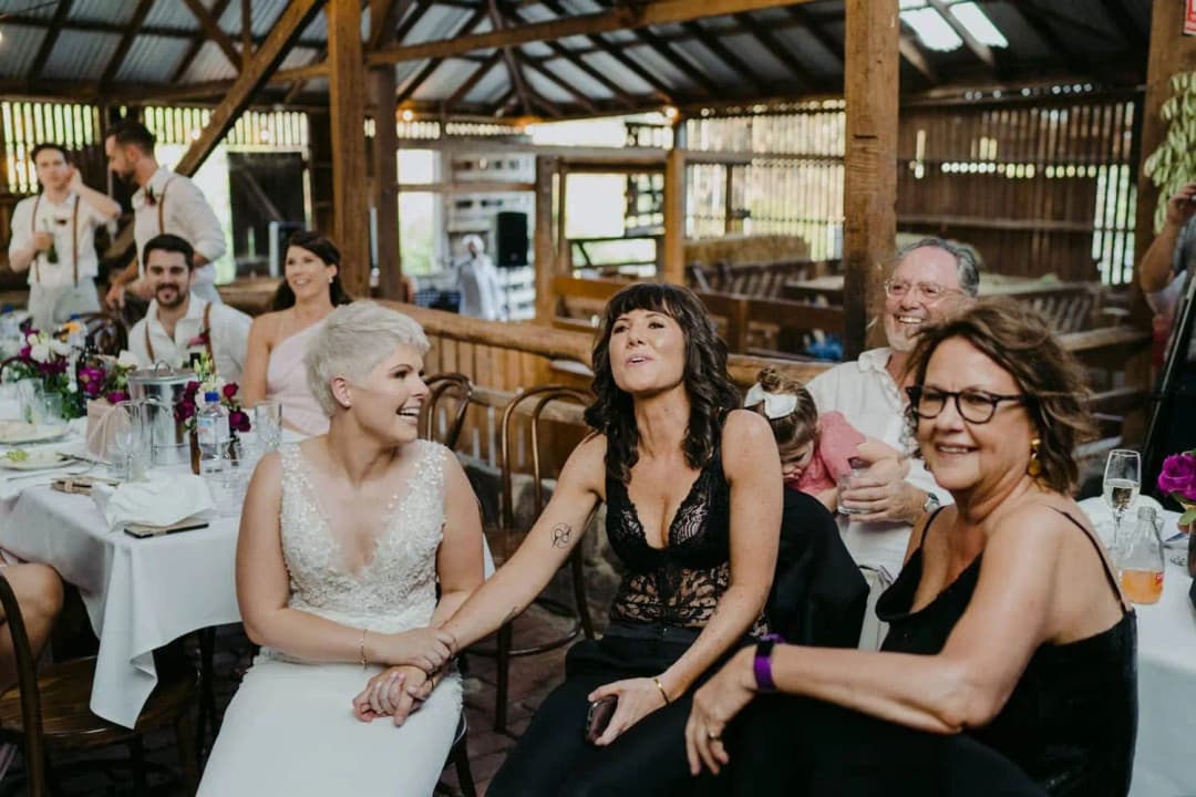 Couple and guests laughing while seated along a reception table
