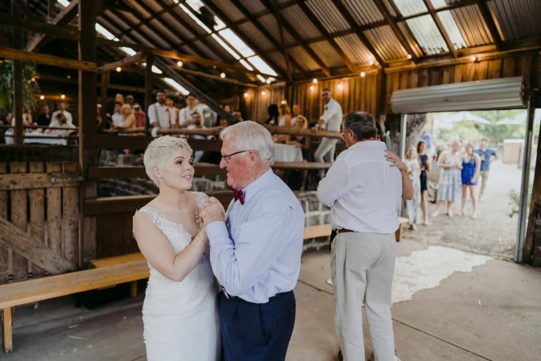 Bride dancing with an older man in a white shirt and bow tie