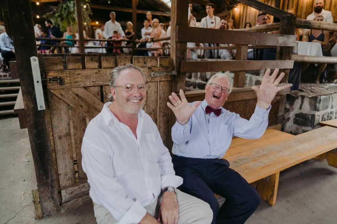 Two older guests laughing while seated on a wooden bench