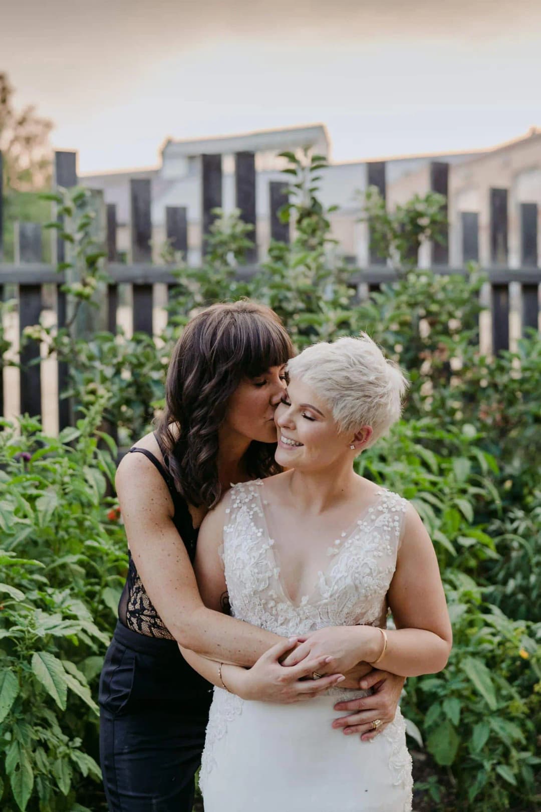 Couple embracing and smiling beside a garden fence