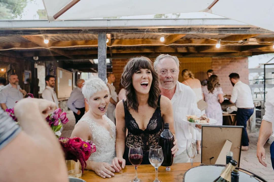 Couple laughing beside a reception table with drinks