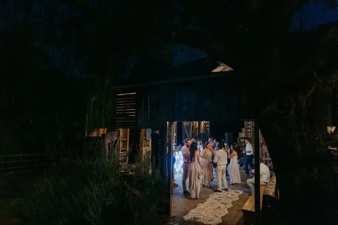 Guests gathered in a brightly lit barn doorway at night