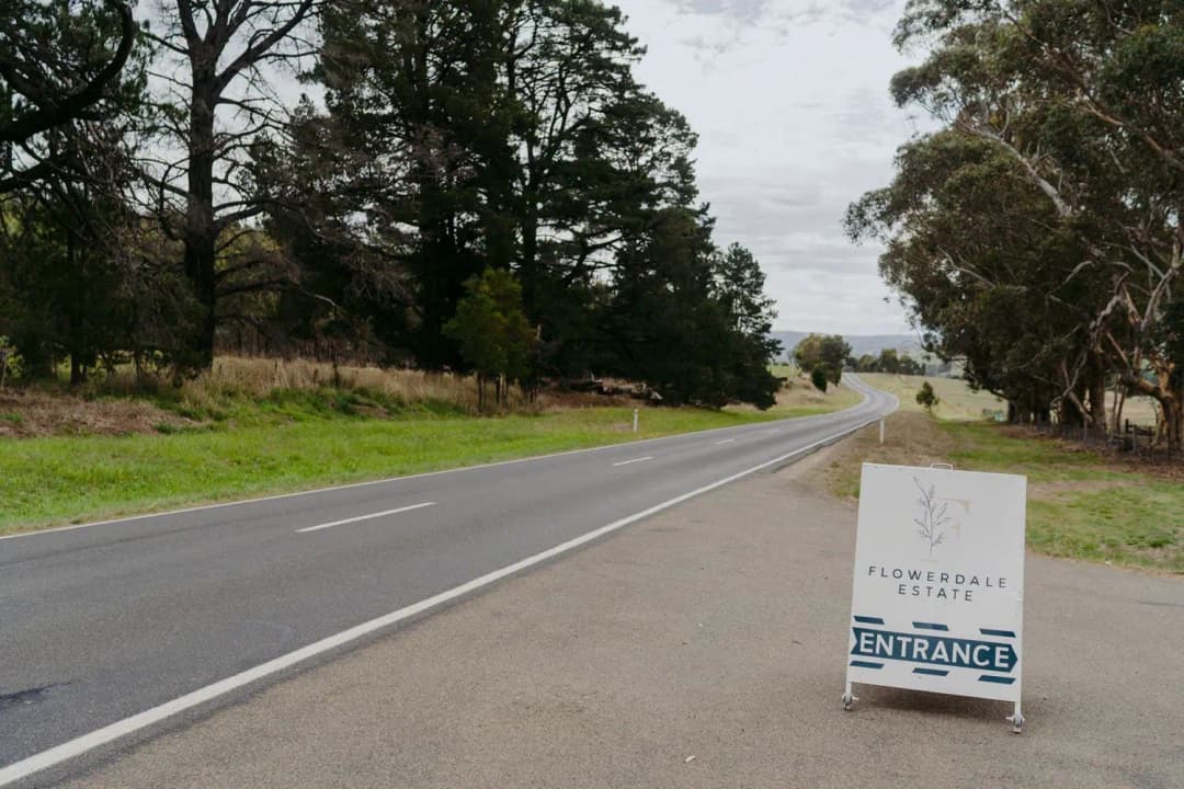 Wedding venue entrance sign beside a tree-lined road