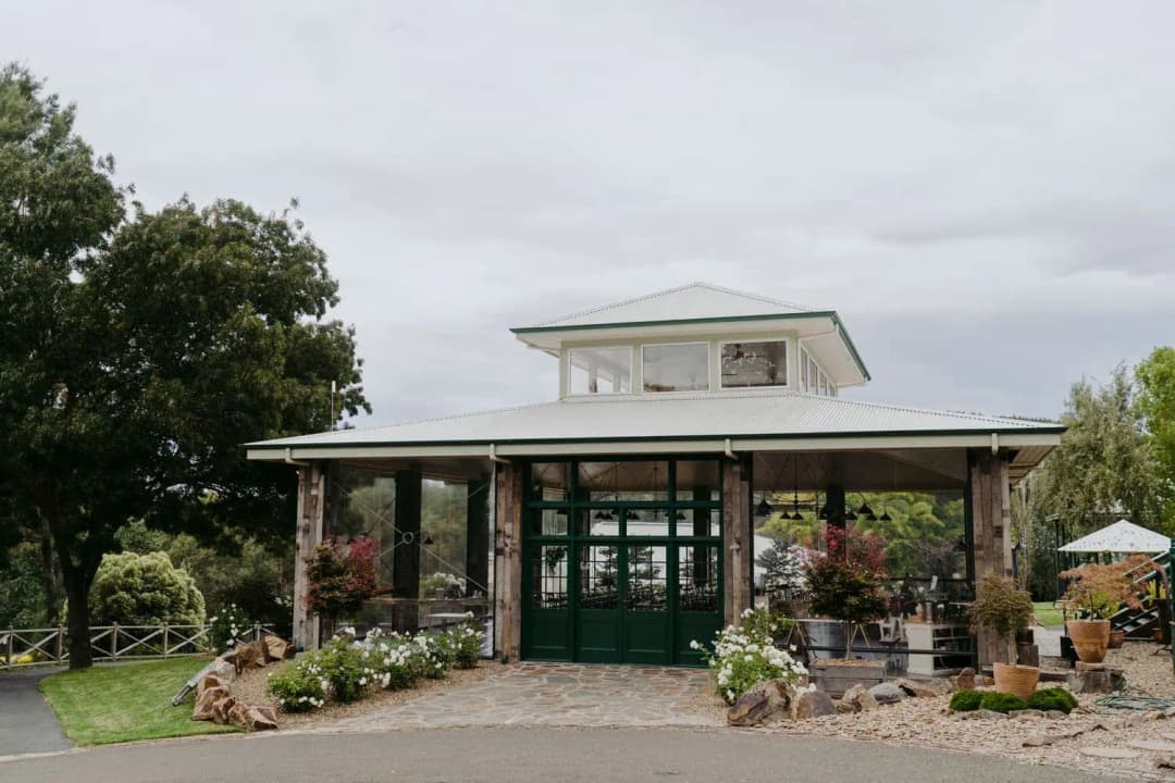 Stone-fronted wedding venue building with green doors and garden beds