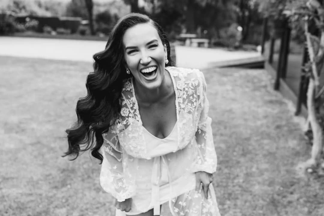 Black and white photograph of a woman laughing outdoors in a lace-trimmed robe