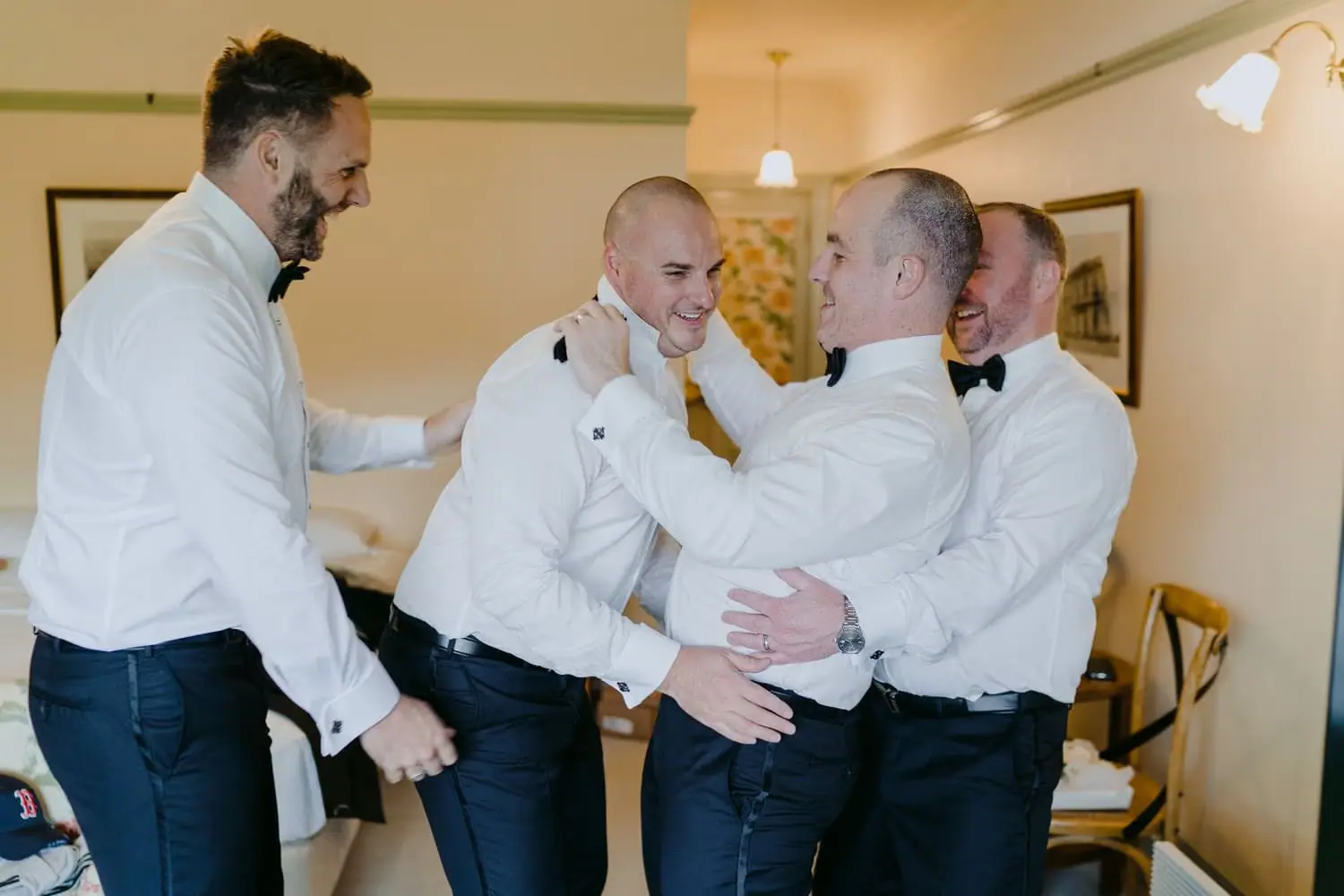 Men helping each other get dressed in white shirts before the wedding