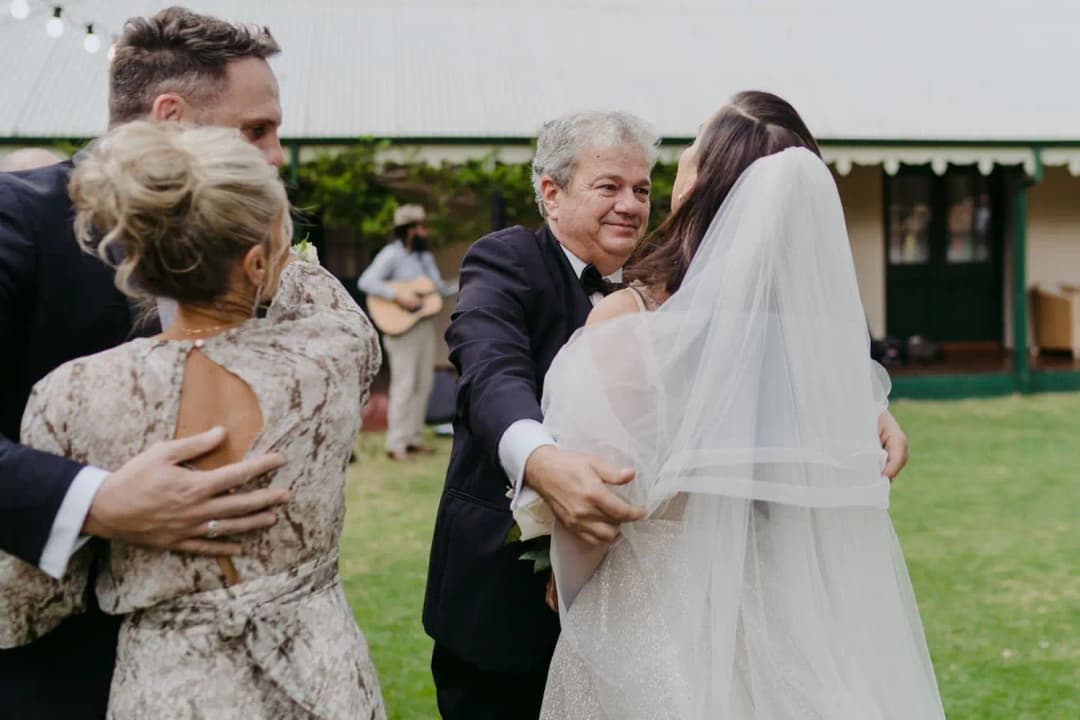Bride and groom embracing guests at the beginning of the garden ceremony