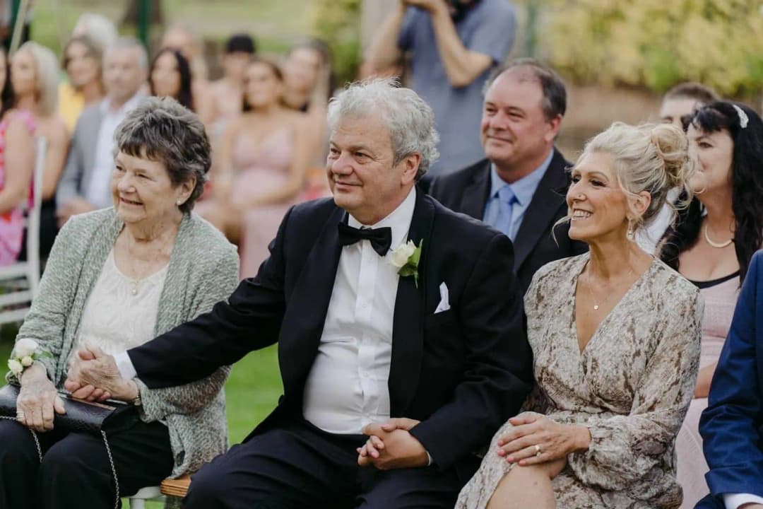 Wedding guests smiling while seated in the front row of the garden ceremony