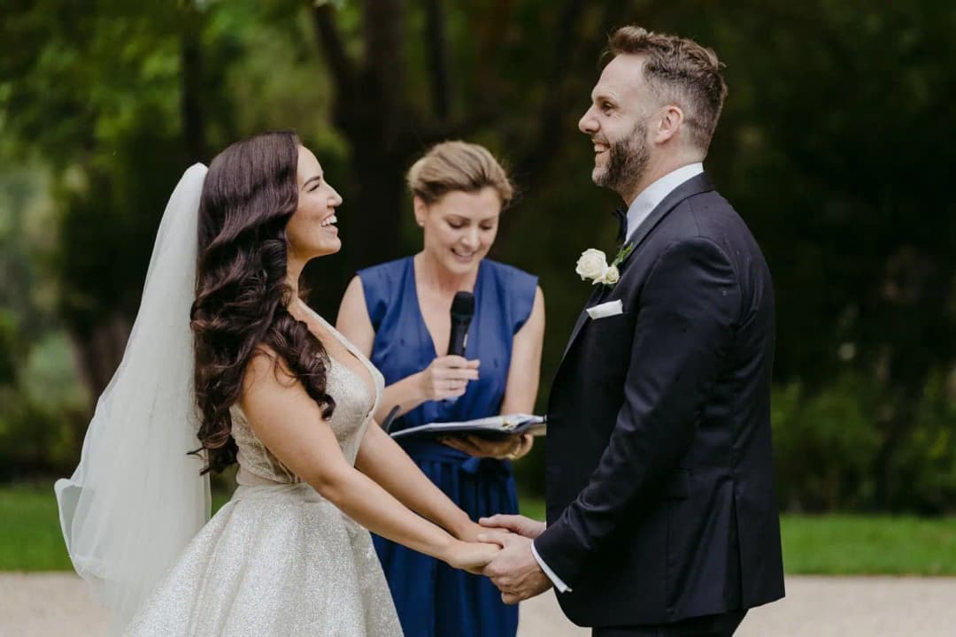 Bride and groom holding hands while the celebrant reads from a book