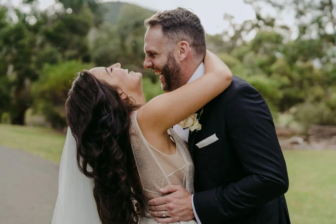 Bride laughing with her arms around the groom's neck