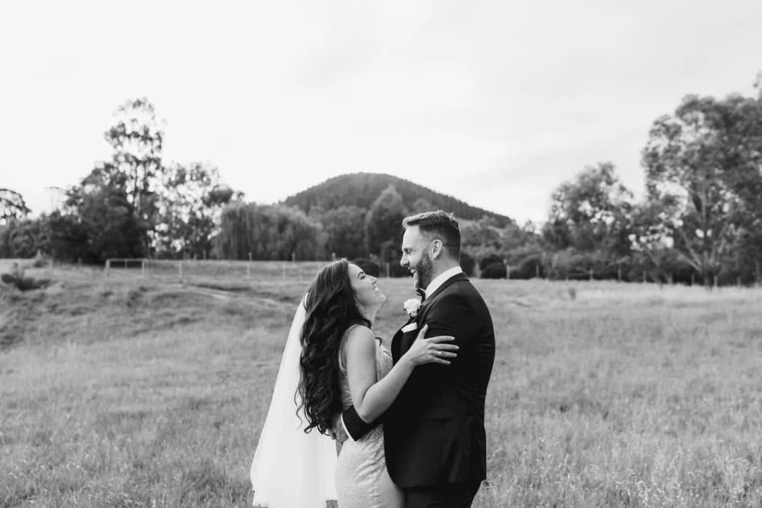 Black and white photograph of the bride and groom embracing in a field